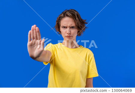 Serious woman demonstrates stop forbidden gesture, assertive body language Serious woman demonstrates stop forbidden gesture, assertive body language 130064069