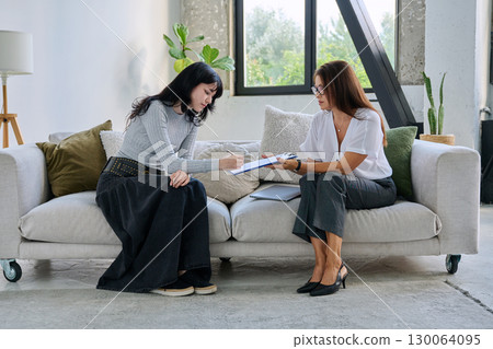 Young female patient in therapy session talking with female psychologist 130064095
