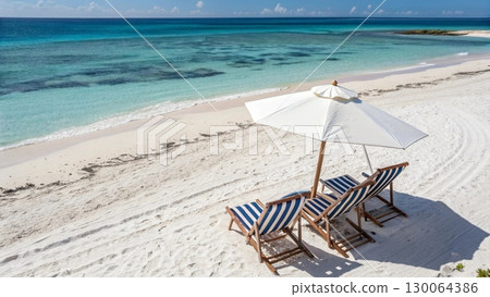 Scenic tropical beach with two colorful striped deck chairs under a large parasol Scenic tropical beach with two colorful striped deck chairs under a large parasol 130064386
