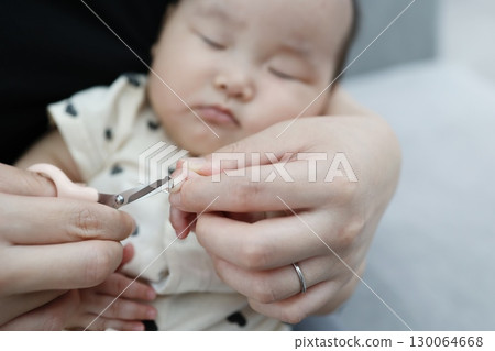 A 6-month-old baby having his nails gently trimmed with scissors A 6-month-old baby having his nails gently trimmed with scissors 130064668