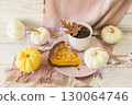 Autumn still life with pumpkin pie, cup of coffee and various decorative pumpkins against a wooden surface and a warm blanket. 130064746