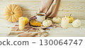 Autumn still life with pumpkin pie, cup of coffee and various decorative pumpkins against a wooden surface and a warm blanket. 130064747