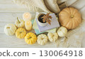 Cozy autumn still life with coffee, wool blanket, pumpkins, candles and books. Seasonal still life. 130064918