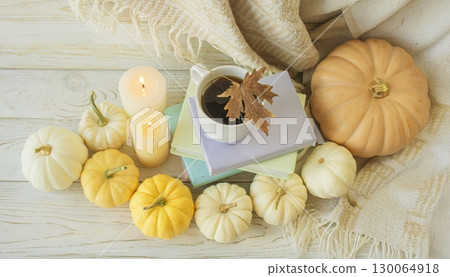 Cozy autumn still life with coffee, wool blanket, pumpkins, candles and books. Seasonal still life. 130064918