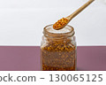 Wooden spoon with chili flakes above glass jar spicy seasoning dried red pepper kitchen ingredient aromatic culinary flavor enhancer food preparation 130065125