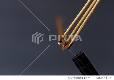 Burning incense stick smoke flame aromatic meditation relaxation spiritual dark background calming ritual. Burning incense sticks with visible flame and smoke create calming and spiritual Burning incense stick smoke flame aromatic meditation relaxation spiritual dark background calming ritual. Burning incense sticks with visible flame and smoke create calming and spiritual 130065126