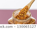 Wooden spoon with chili flakes spicy seasoning glass jar close up kitchen ingredient aromatic red color cooking flavor enhancer rustic style 130065127