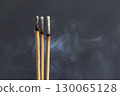Burning incense sticks smoke aromatic meditation relaxation spiritual calming fragrant ritual wellness. Three incense sticks burning with gentle smoke swirling air creating calming and spiritual 130065128