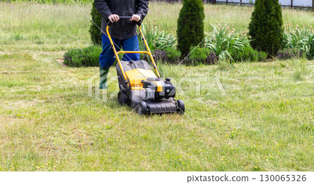 Grass mowing in spring, garden tool - lawn mower 130065326