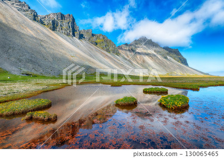 Amazing sunny day and gorgeous meadow near Vestrahorn mountaine on Stokksnes cape in Iceland. Amazing sunny day and gorgeous meadow near Vestrahorn mountaine on Stokksnes cape in Iceland. 130065465