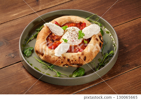 Delicious italian style pizza with egg, tomato sauce, and cheese on wooden table 130065665