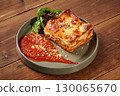 Delicious lasagna bolognese with tomato sauce and parmesan on wooden table 130065670