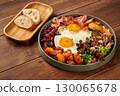 Delicious breakfast consisting of fried eggs, bacon, beans, chicken, potatoes and salad on wooden table 130065678