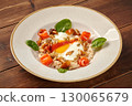 Oatmeal porridge with fried eggs, salmon, mushrooms, and greens on wooden table 130065679