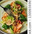 Fork taking a bite of fresh salmon salad with seaweed and lettuce 130065690