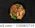 Soba noodles with chicken, spinach, and sesame seeds in black bowl 130065719