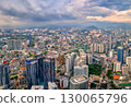Panoramic aerial view, Kuala Lumpur, Malaysia, urban skyline, high-rise buildings, suburban areas, mountains in background, dense city architecture, transportation networks, dramatic sky at daytime 130065796