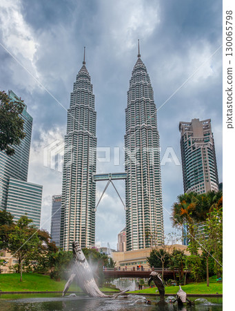 Nov 20, 2019 - Kuala Lumpur, Malaysia: Petronas Twin Towers with skybridge in urban skyline during daytime under dramatic cloudy sky. Scenic cityscape with lush park, pond, bridge and modern Whale and 130065798