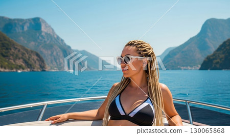 Stylish Woman Relaxing on Luxury Yacht Deck Surrounded by Dramatic Mediterranean Coastline 130065868