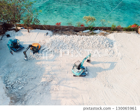 Construction site with excavators moving white rocks near turquoise sea, aerial view 130065961