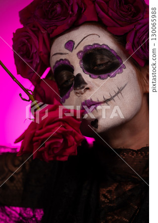 Girl With Sugar Skull Makeup Holds a Red Rose for Dia De Los Muertos 130065988