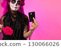 Woman With Sugar Skull Makeup Holding Black Credit Card on Dia De Muertos 130066026