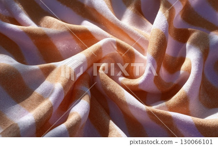 Luxurious silk fabric swirls creating elegant waves with warm golden sunset lighting effects 130066101