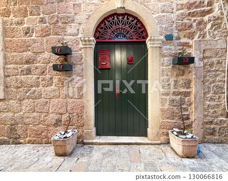 A dark green door with a red mailbox decorates a stone wall. Tradition, communication and historical architecture. A dark green door with a red mailbox decorates a stone wall. Tradition, communication and historical architecture. 130066816