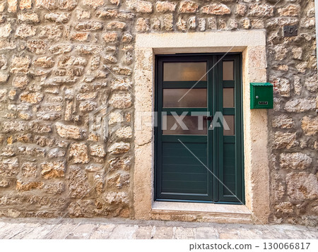 A green door with a mailbox stands in a stone wall. Urban architecture, residential life and traditional exterior detail. A green door with a mailbox stands in a stone wall. Urban architecture, residential life and traditional exterior detail. 130066817