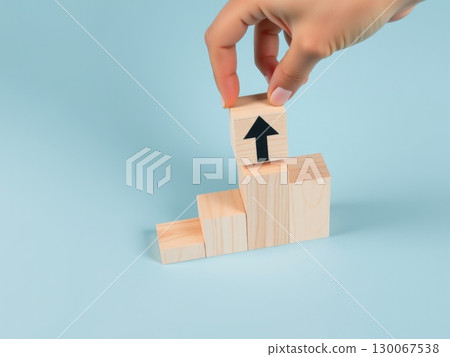 Hand Stacking Wooden Blocks with Upward Arrows 130067538