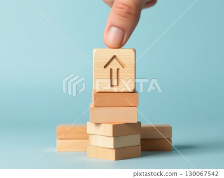 Hand Stacking Wooden Blocks with Upward Arrows 130067542