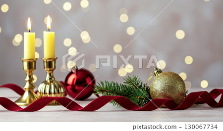 Holiday candles and ornaments on a table with a red ribbon and sparkling lights. Christmas atmosphere. 130067734