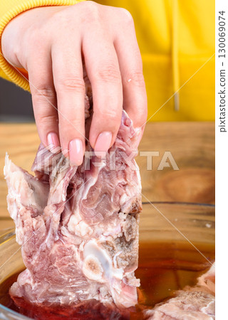 Raw beef meat in a woman's hand from a bowl of water. Raw beef meat in a woman's hand from a bowl of water. 130069074
