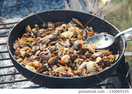 Cooking fried mussels in frying pan macro. Frying fresh mussels and onions 130069195