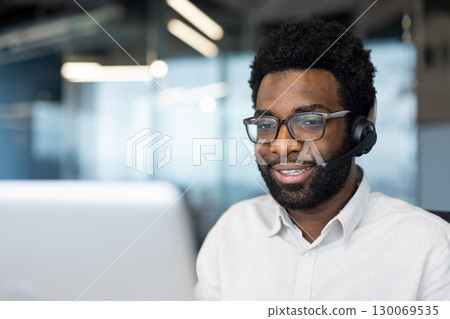 Customer service representative wearing a headset and glasses, working in a modern office space. Displays friendly and professional communication in a business environment Customer service representative wearing a headset and glasses, working in a modern office space. Displays friendly and professional communication in a business environment 130069535