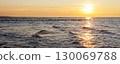 Scenic warm sea sunset view golden sunset over Baltic Sea reflects across rippling waves, creating a glowing path of light. Wooden breakwaters stretch into horizon calm rhythm to tranquil seascape 130069788