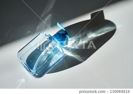 Hand washing gel in a blue bottle with a dispenser on a white background. 130069816