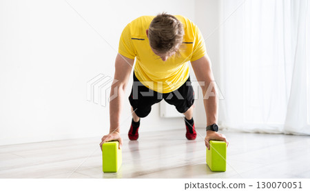 Young Man Doing Routine Sport At Home With Yoga Blocks 130070051