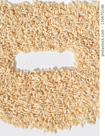 Close up of uncooked brown rice grains arranged in letter c shape on white Close up of uncooked brown rice grains arranged in letter c shape on white 130070196
