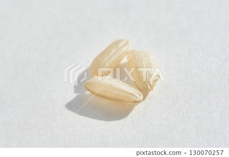 Close up of three uncooked white rice grains on bright white background 130070257
