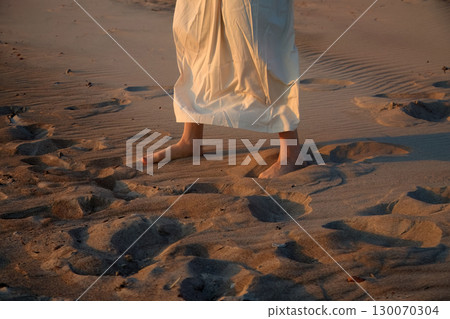 Serenity on the Sand. Silhouette of feet on a sandy beach at sunse Serenity on the Sand. Silhouette of feet on a sandy beach at sunse 130070304