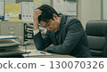 A businessman holding his head and thinking with a serious expression about work worries in the office 130070326