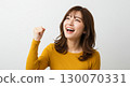 A young Japanese woman making a fist pump with her right hand and looking diagonally upwards - motivating herself to achieve her dreams and goals 130070331