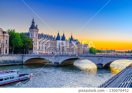 Paris city historic center with Pont au Change bridge across Seine river, Conciergerie palace building on de la Cite island on sunset twilight, Paris cityscape evening view, France 130070452
