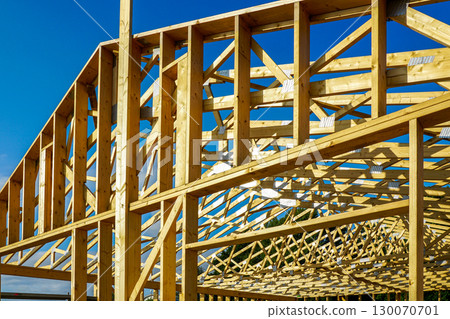 Wooden frame structure of house under construction against blue sky at building site Wooden frame structure of house under construction against blue sky at building site 130070701