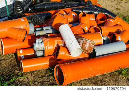 Pile of orange and gray plastic pipes and fittings at construction site for drainage system Pile of orange and gray plastic pipes and fittings at construction site for drainage system 130070704