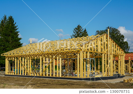 New modern wooden house frame construction with roof trusses under blue sky on building site New modern wooden house frame construction with roof trusses under blue sky on building site 130070731