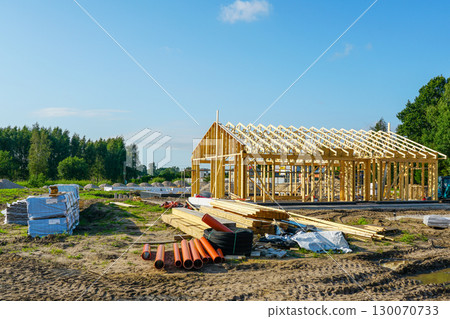 New modern wooden house construction with timber framing and building materials on site New modern wooden house construction with timber framing and building materials on site 130070733