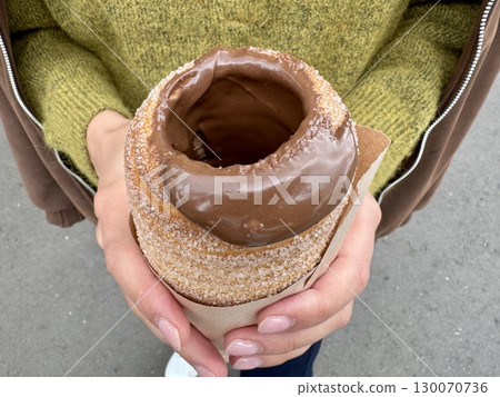 sweet trdelnik with nutella in the hands of a girl in summer. High quality photo sweet trdelnik with nutella in the hands of a girl in summer. High quality photo 130070736