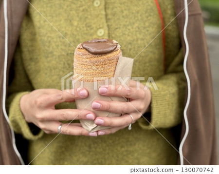 sweet trdelnik with nutella in the hands of a girl in summer. High quality photo sweet trdelnik with nutella in the hands of a girl in summer. High quality photo 130070742